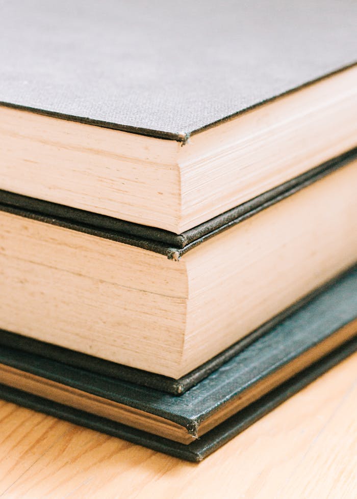 A close-up image of a stack of hardcover books on a wooden surface.